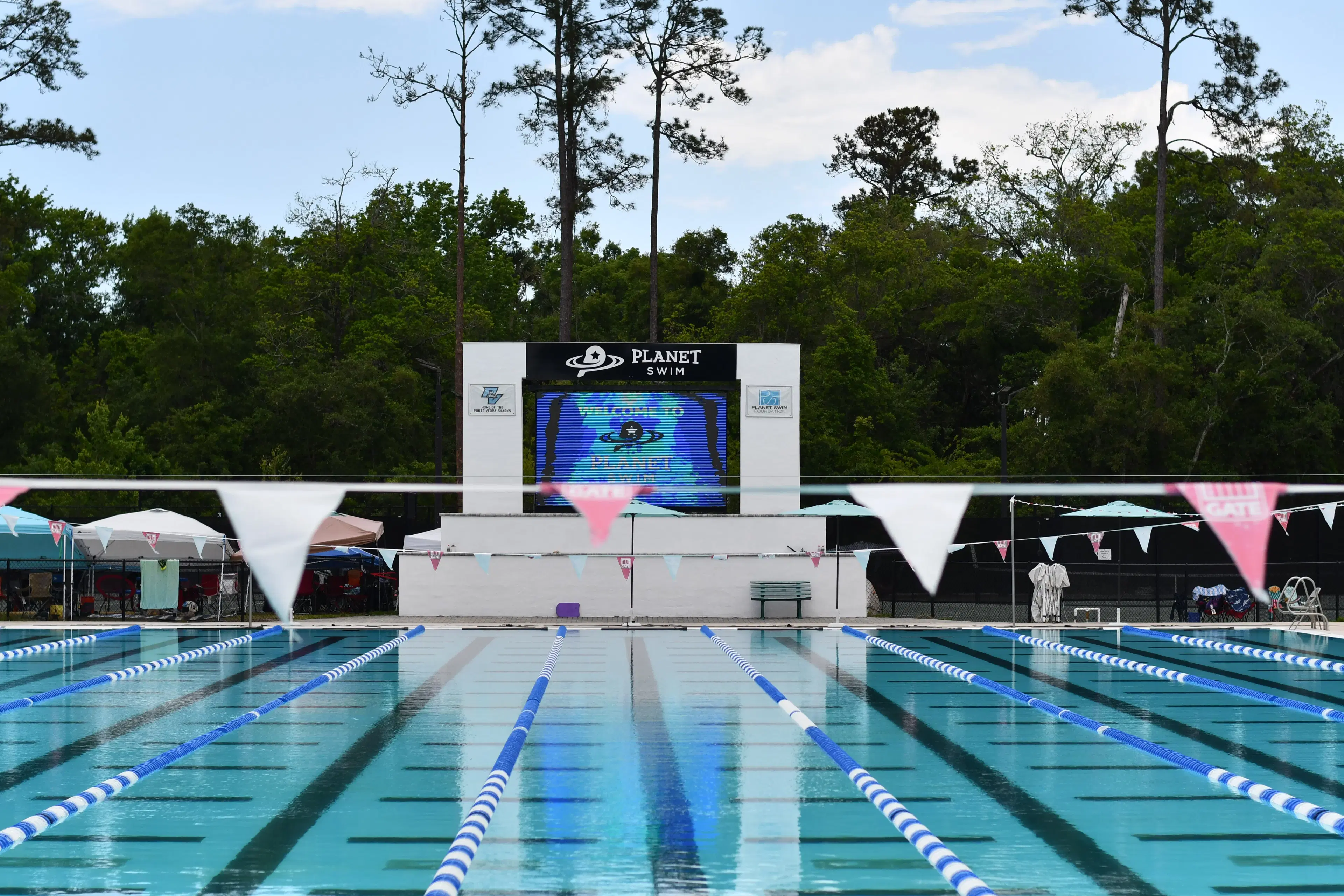 The Planet Swim outdoor pool with lane lines and the club scoreboard